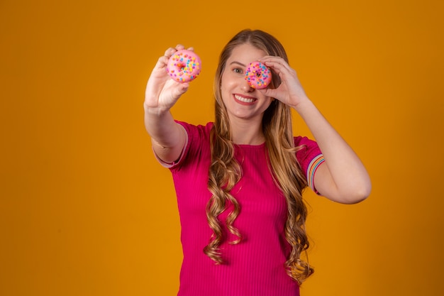 Young blonde with donuts on yellow background