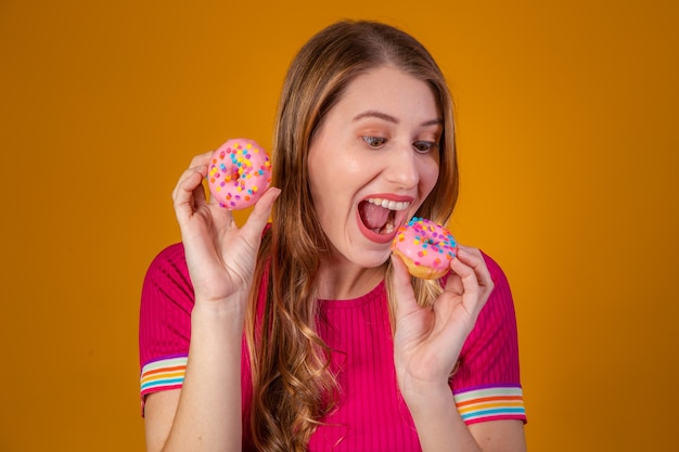 Young blonde with donuts on yellow background