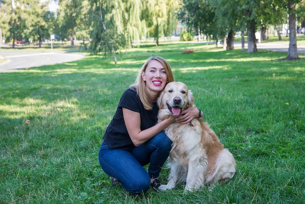 Young blonde with her retriever dog outdoors.