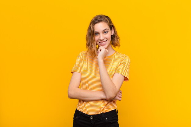 Young blonde woman  against flat color wall