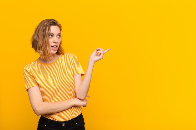 Young blonde woman against flat color wall