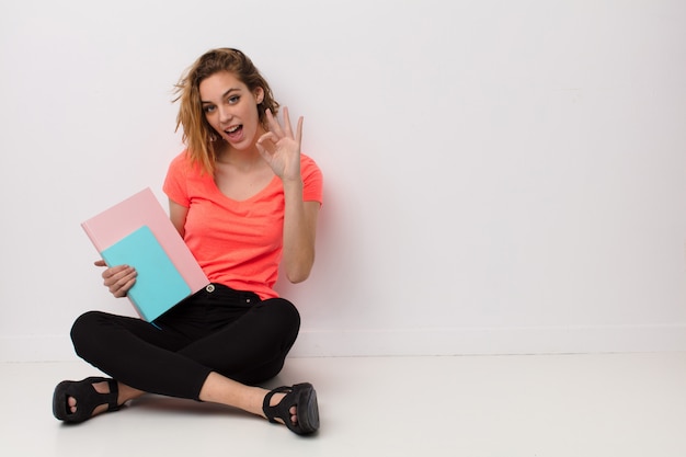 Young blonde woman  against  wall with books