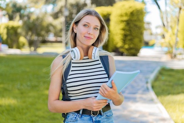 写真 屋外でノートを持っている若いブロンドの女性