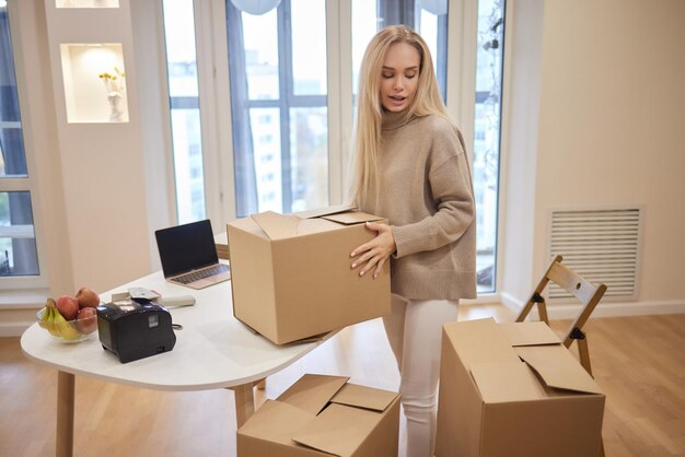 Young blonde woman barcode printer and boxes on the background for market places