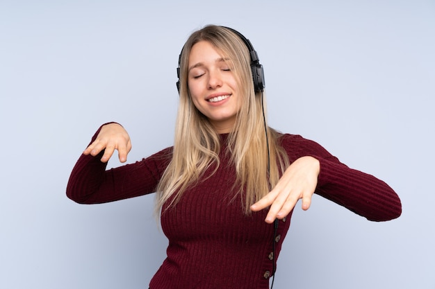 Giovane donna bionda sopra musica e ballare d'ascolto blu