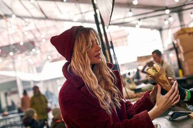 young blonde woman buying sandwich at sandwich bar
