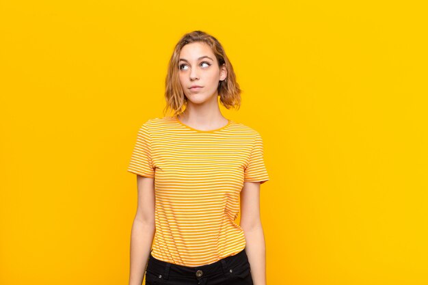 Young blonde woman over color wall