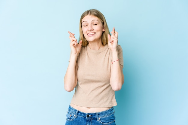 Young blonde woman crossing fingers for having luck