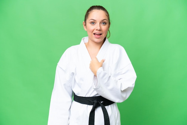 Young blonde woman doing karate over isolated chroma key background with surprise facial expression