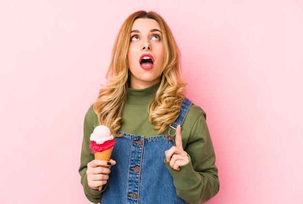 Foto giovane donna bionda che mangia un gelato isolato rivolto verso l'alto con la bocca aperta.