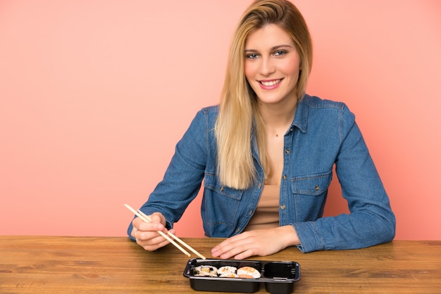 Молодая блондинка ест суши