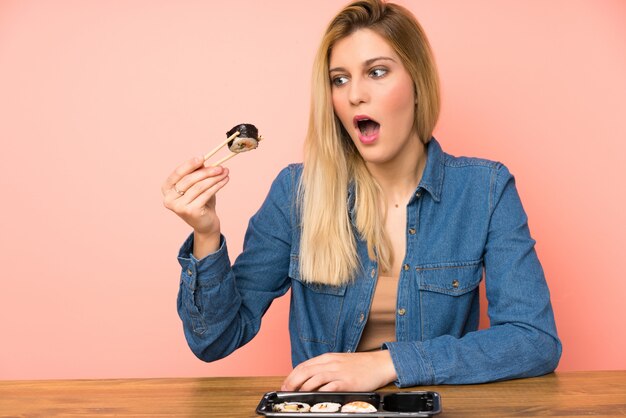 Young blonde woman eating sushi