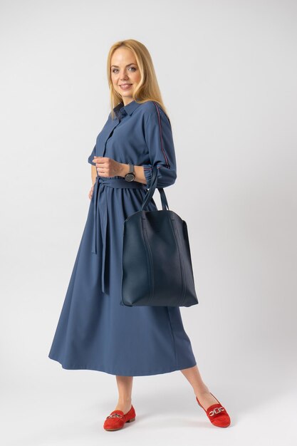 Young blonde woman in an elegant casual fashionable dress with a bag in her hands