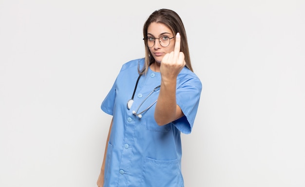 Young blonde woman feeling angry, annoyed, rebellious and aggressive, flipping the middle finger, fighting back