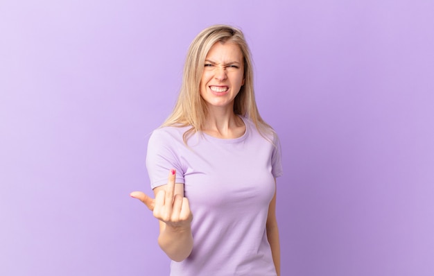 Young blonde woman feeling angry, annoyed, rebellious and aggressive