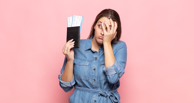 Young blonde woman feeling bored, frustrated and sleepy after a tiresome, dull and tedious task, holding face with hand