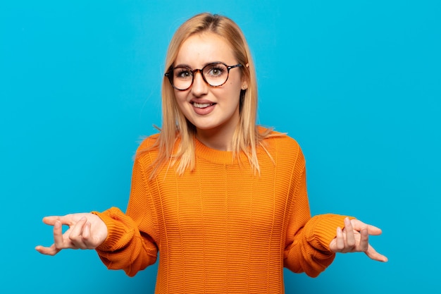 Young blonde woman feeling clueless and confused, having no idea, absolutely puzzled with a dumb or foolish look