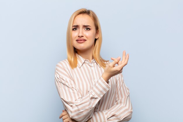 Young blonde woman feeling confused and clueless, wondering about a doubtful explanation or thought