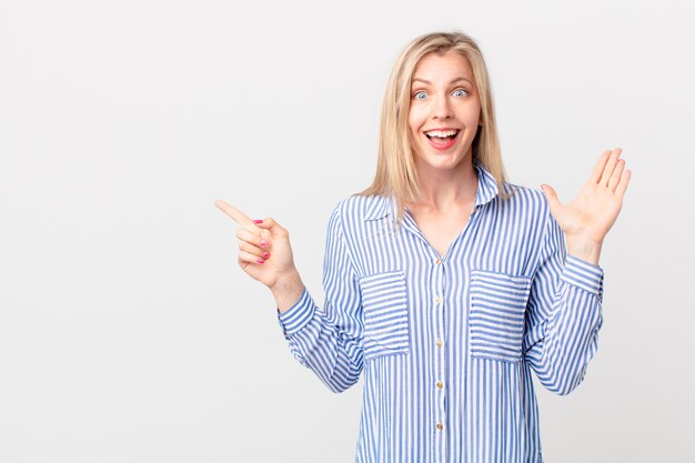 Young blonde woman feeling happy and astonished at something unbelievable