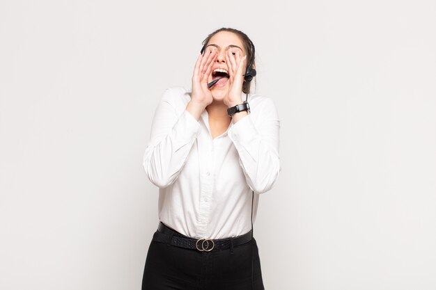 Young blonde woman feeling happy, excited and positive, giving a big shout out with hands next to mouth