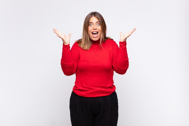 Young blonde woman feeling happy, excited, surprised or shocked, smiling and astonished at something unbelievable