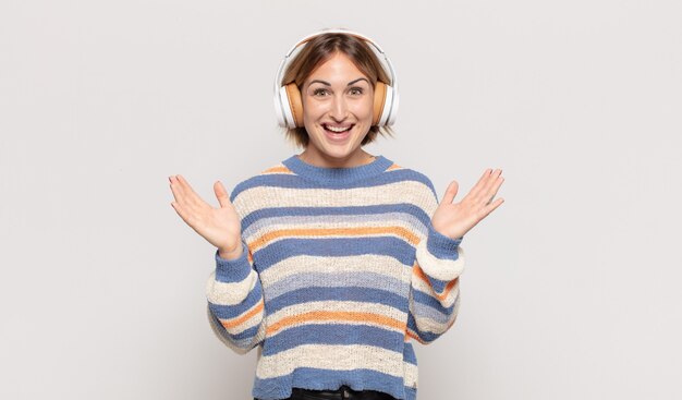 Young blonde woman feeling happy, excited, surprised or shocked, smiling and astonished at something unbelievable