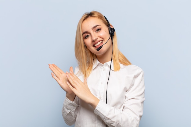 Young blonde woman feeling happy and successful, smiling and clapping hands, saying congratulations with an applause