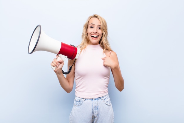 Young blonde woman feeling happy, surprised and proud