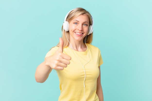 Young blonde woman feeling proud,smiling positively with thumbs up and listening music.