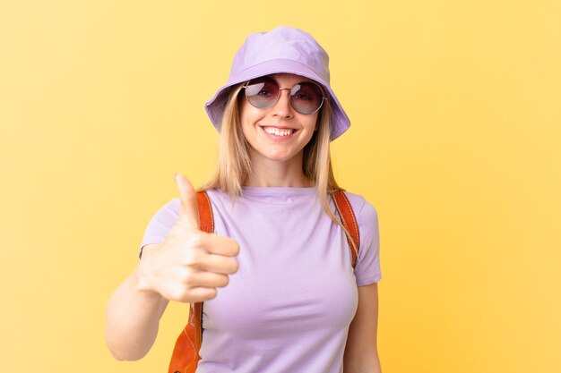 Young blonde woman feeling proud,smiling positively with thumbs up