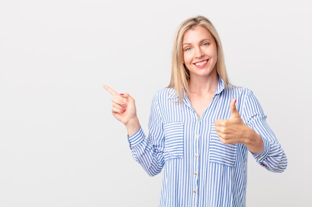 Young blonde woman feeling proud,smiling positively with thumbs up