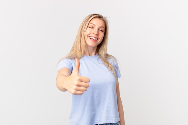 Young blonde woman feeling proud,smiling positively with thumbs up