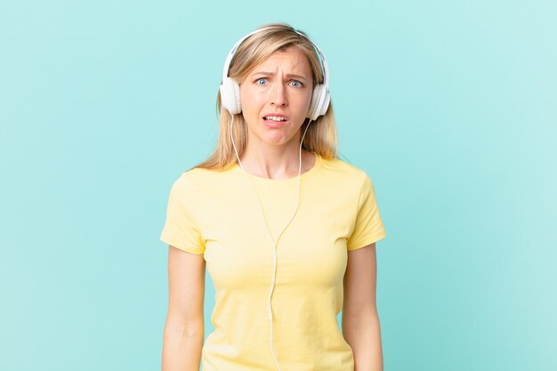 Photo young blonde woman feeling puzzled and confused and listening music