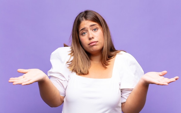 Young blonde woman feeling puzzled and confused, unsure about the correct answer or decision, trying to make a choice