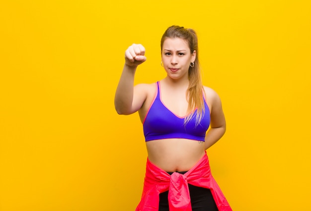 Giovane donna bionda sentendosi seria, forte e ribelle, alzando il pugno, protestando o combattendo per la rivoluzione. concetto di sport