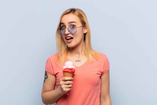 Young blonde woman feeling shocked, happy, amazed and surprised, looking to the side with open mouth