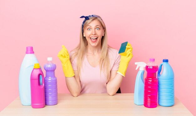 Young blonde woman feeling shocked,laughing and celebrating success. housekeeper concept