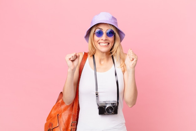 Young blonde woman feeling shocked,laughing and celebrating success