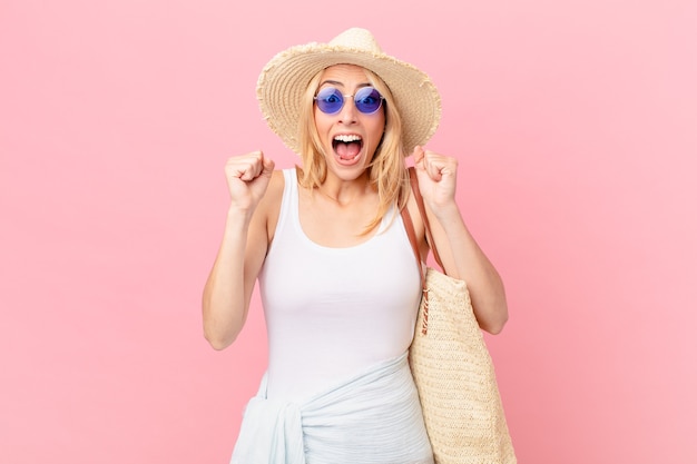 Young blonde woman feeling shocked,laughing and celebrating success