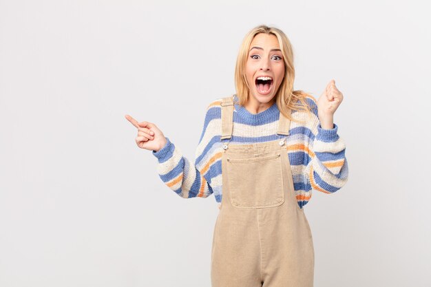 Young blonde woman feeling shocked,laughing and celebrating success