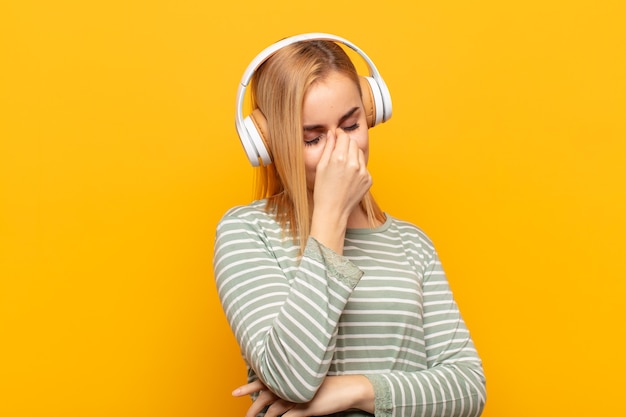 Young blonde woman feeling stressed, unhappy and frustrated, touching forehead and suffering migraine of severe headache