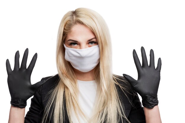 医療マスクと手袋でフォーマルなスーツを着た若いブロンドの女性。コロナウイルスのパンデミックおよびアレルギーシーズン中の保護対策。白で隔離。閉じる。