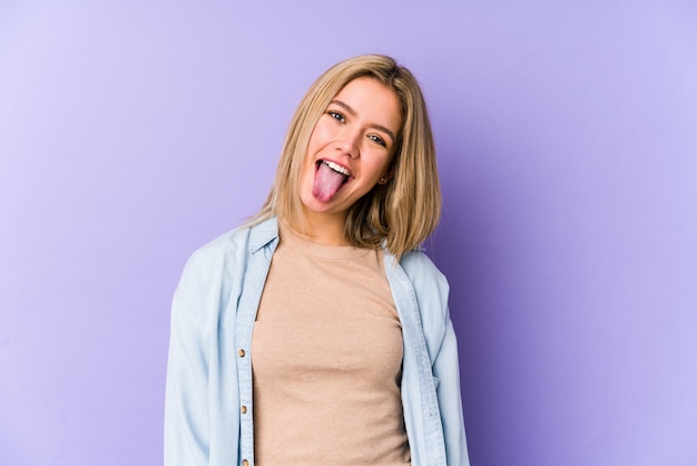 Young blonde woman funny and friendly sticking out tongue