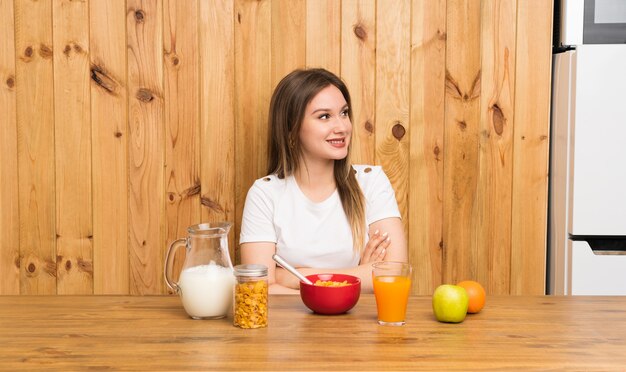 Giovane donna bionda che mangia prima colazione che ride