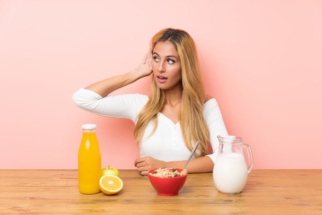 Young blonde woman having breakfast milk listening something