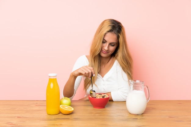 Giovane donna bionda che mangia il latte della prima colazione