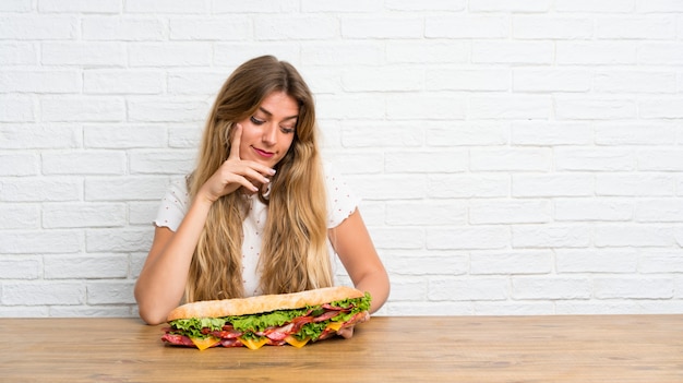 Foto giovane donna bionda che tiene un grande panino