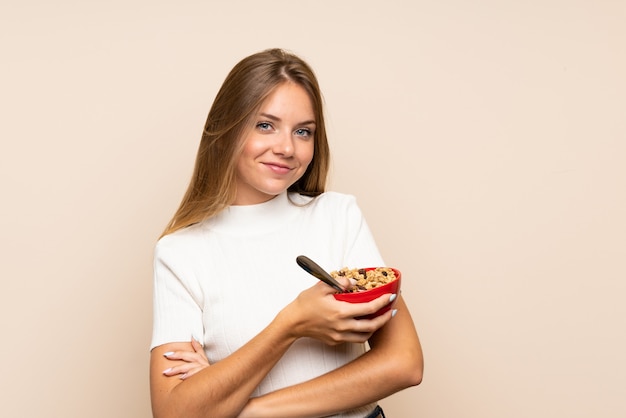 Giovane donna bionda che tiene una ciotola di cereali