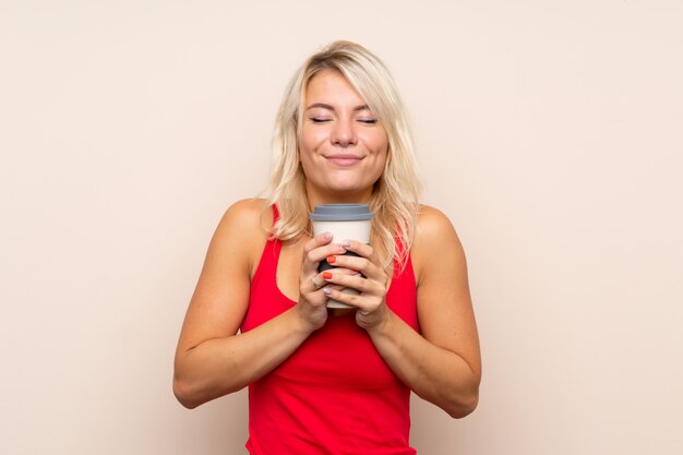 Young blonde woman holding coffee to take away