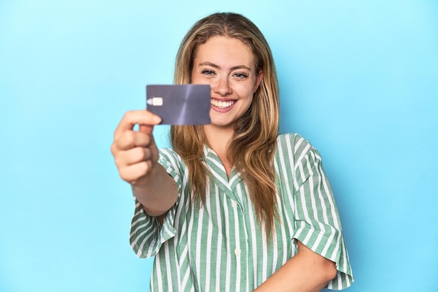 Young blonde woman holding a credit card in a studio